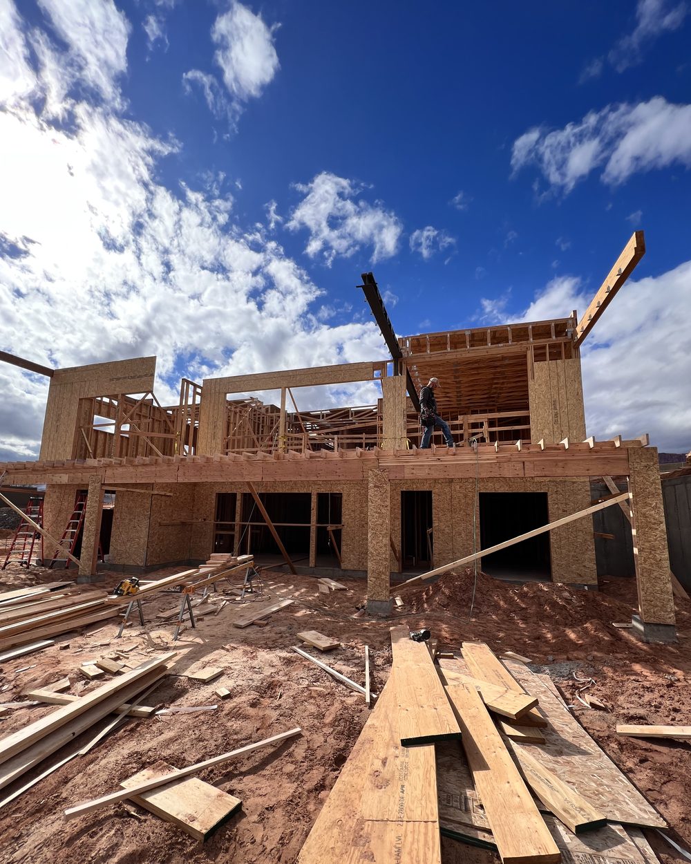 Multi-story wood framing against a blue sky with a framer working on the upper level